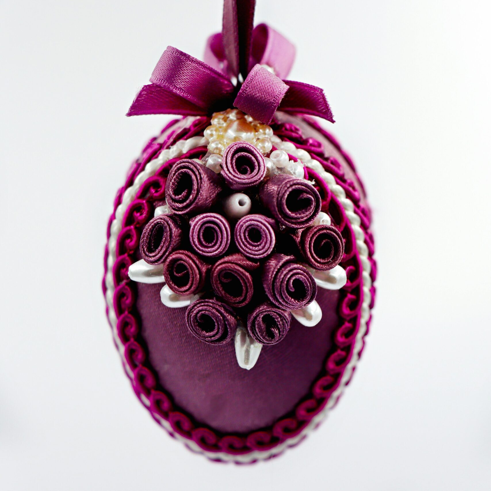 Artistic Easter egg decoration with intricate purple designs and a bow, perfect for spring decor.
